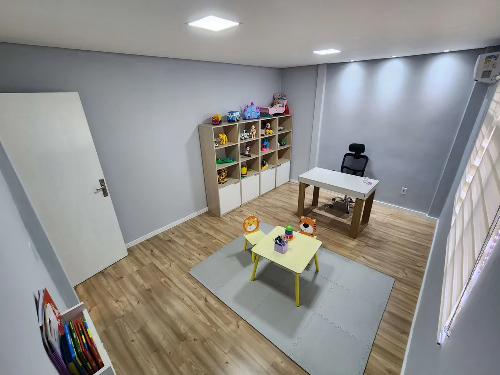 Sala de atendimento climatizada, com estante de brinquedos e mesa infantil.