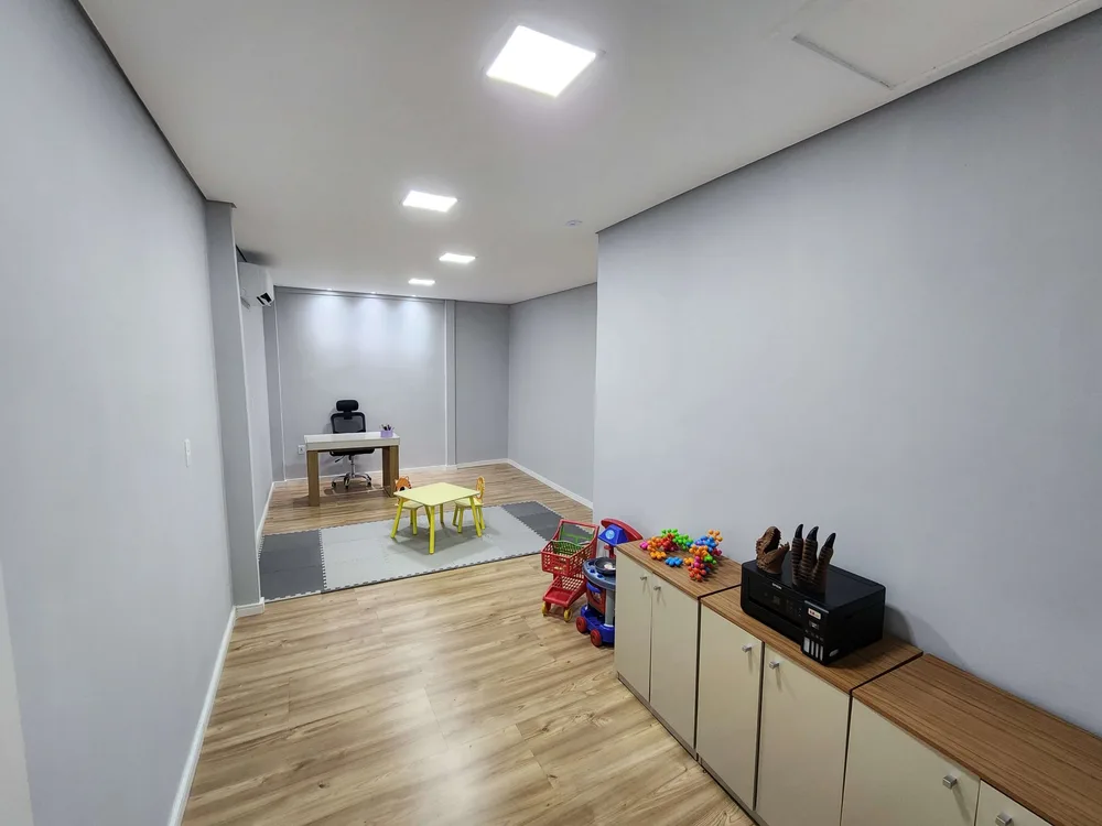 Sala ampla de atendimento com tapete de atividades e brinquedos.