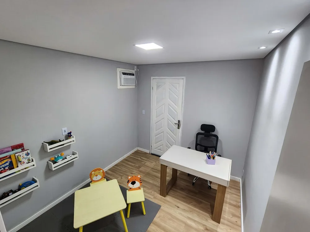Sala de atendimento com mesinha infantil e prateleiras de livros.