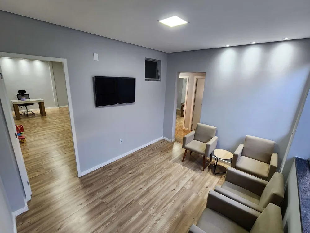 Recepção da clínica, com poltronas e televisão.
